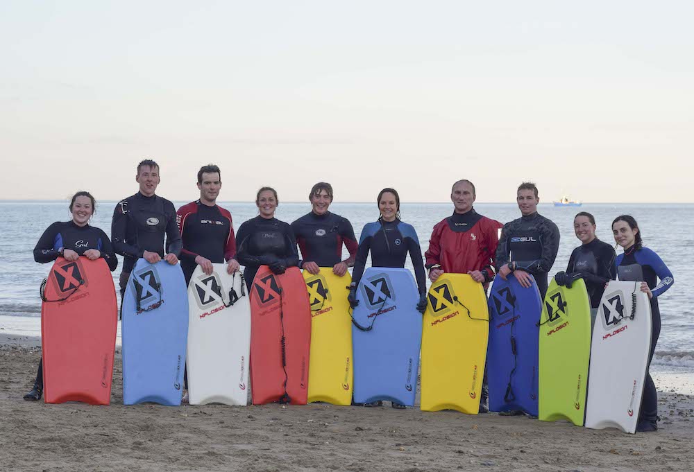A group of people wearing wetsuit on the beach 