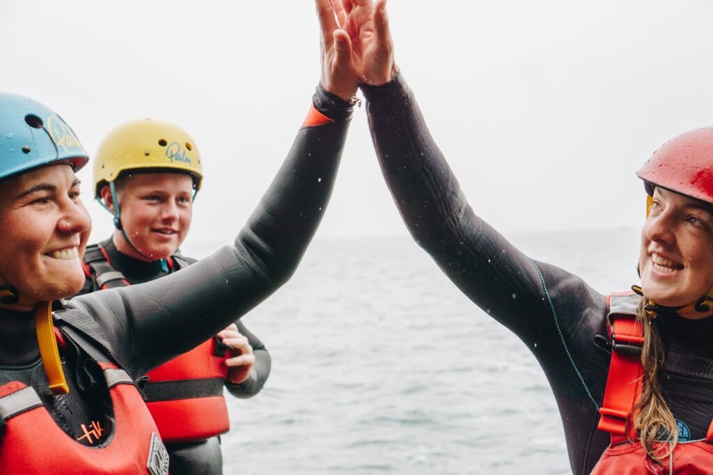 2 Girls with helmets and buoyancy aids on high five