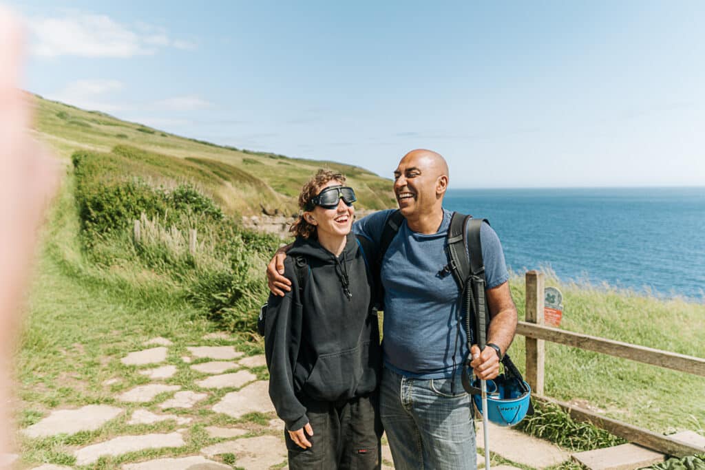 Amar Latif and instructor Verity share a  bonding moment and laugh on top of a cliff top with the sea in the background