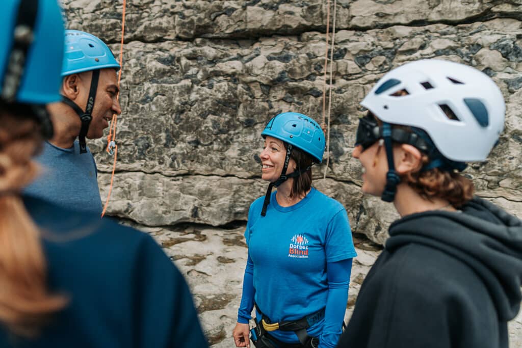 Sam Baker from Dorset Blind Association talks to Amir Latif at the bottom of a grey rock face.