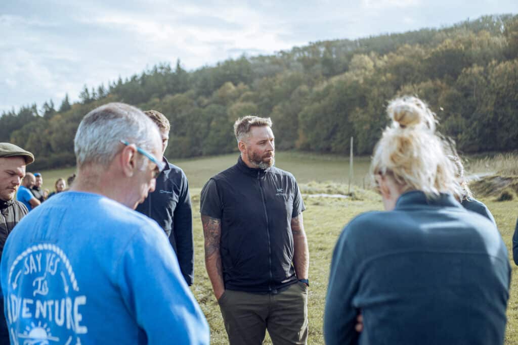 Daniel is an outdoor instructor who has ADHD - he stands outside in a field wearing black clothes