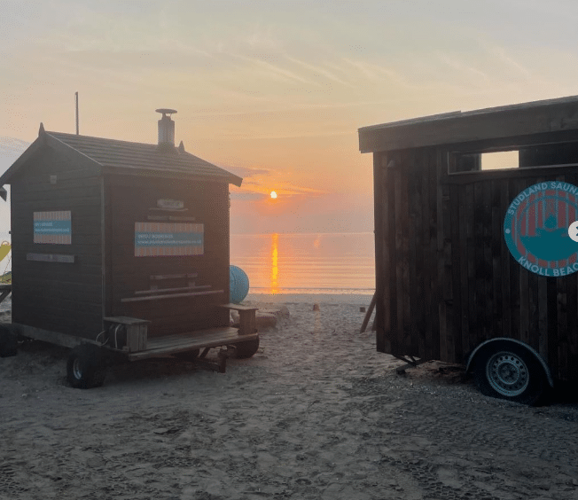 Little hut and big hut on studland beach at sunset