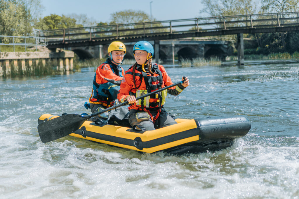a Female at the front of the rescue Raft whilst the male worker is at the back practicing searching