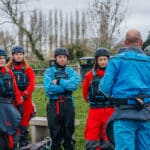 Teacher looking towards group, teaching about kayaking. This is an example of using a AET qualification